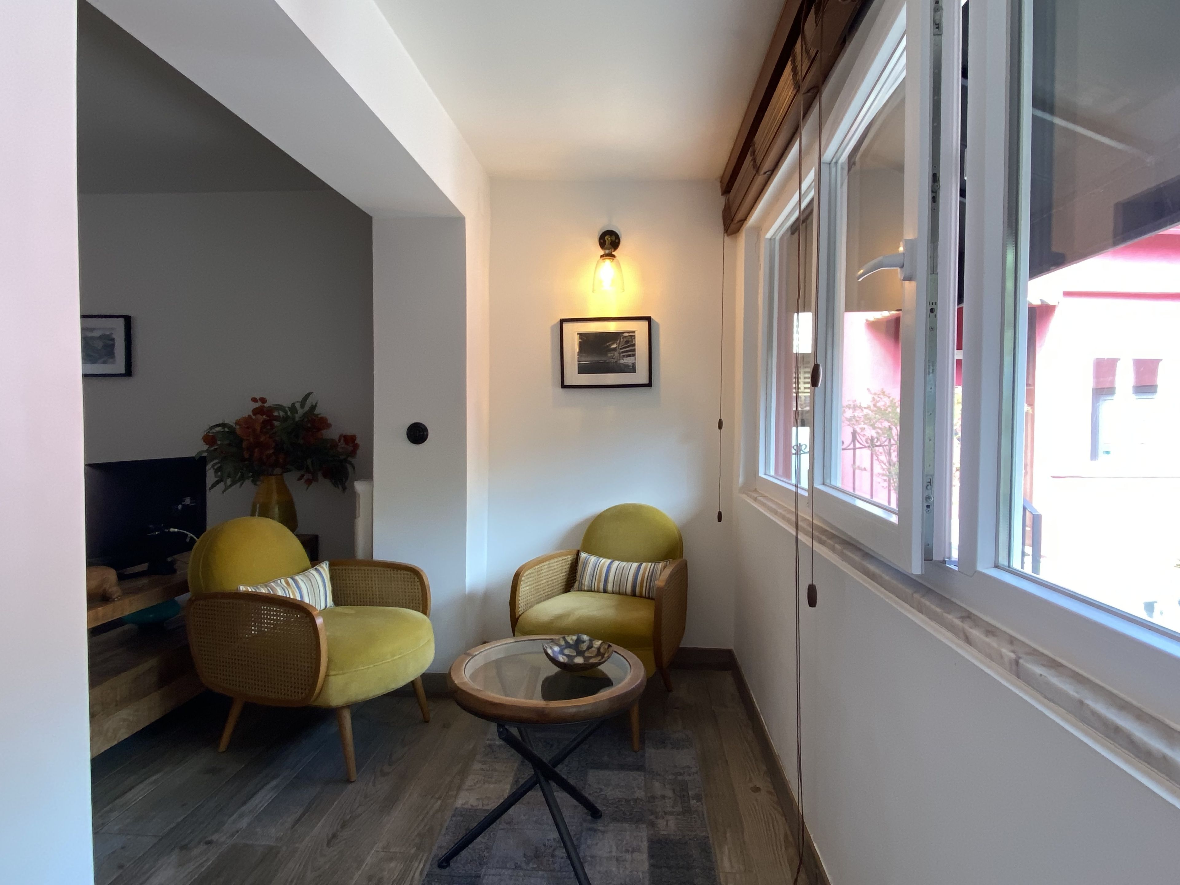 A cozy living area with two yellow armchairs, a small round coffee table, and a television on a wooden stand.