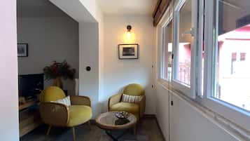 A cozy living area with two yellow armchairs, a small round coffee table, and a television on a wooden stand.