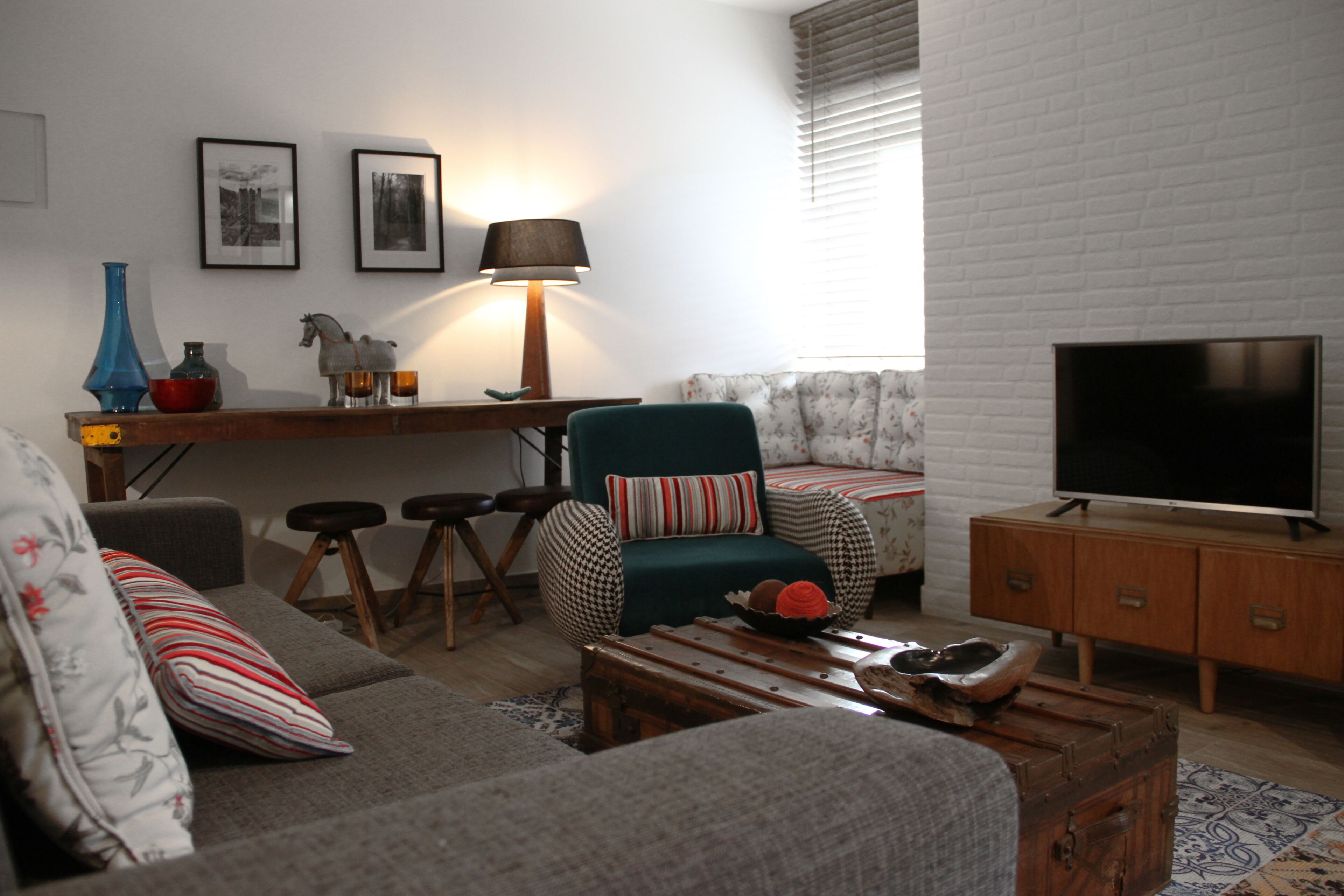 Ein Wohnzimmer mit Sofa, Sessel, Couchtisch, Fernseher und einem kleinen Beistelltisch.