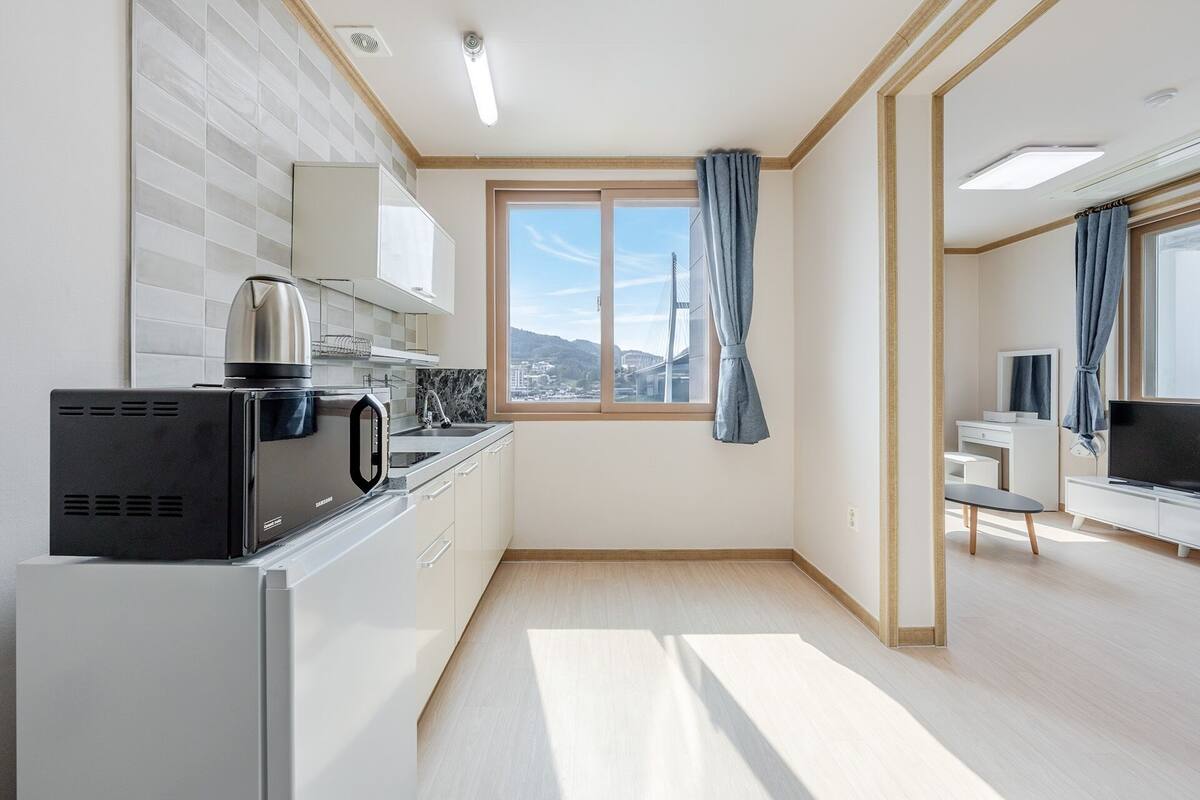 Eine moderne Küche mit integriertem Mikrowellenherd, einem Wasserkocher und einem Fenster mit Vorhängen.