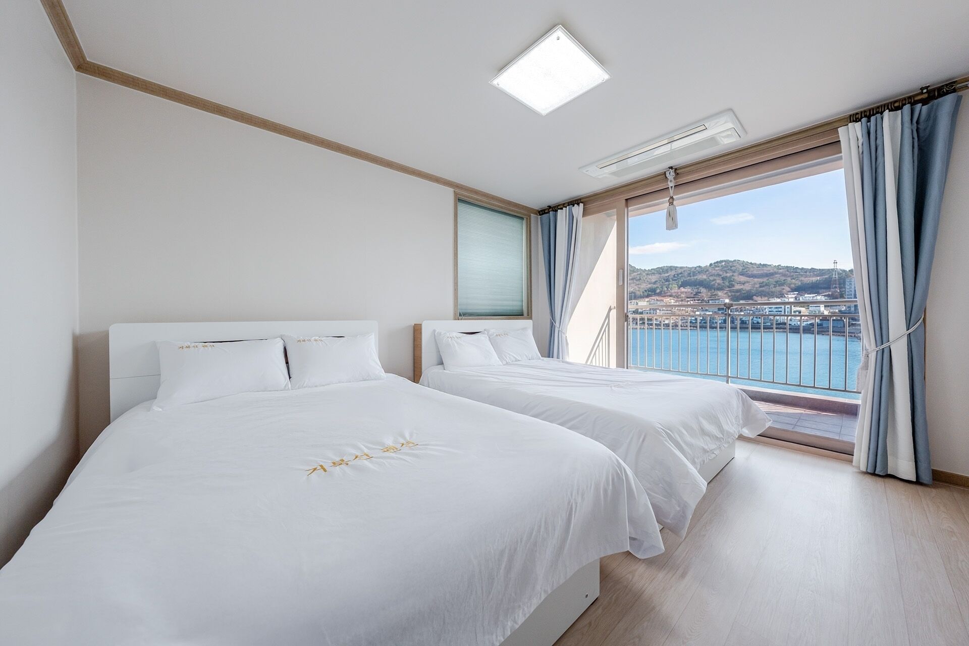 Quarto de hotel com duas camas, vista para o mar e varanda.