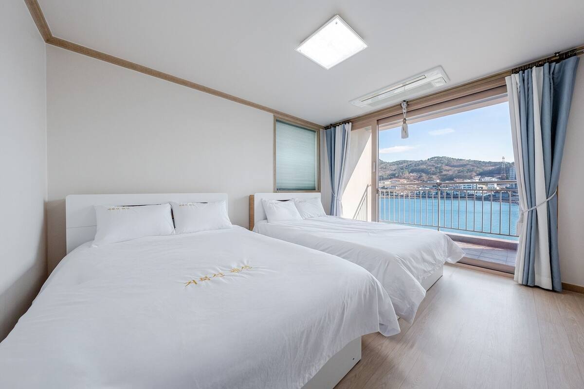 Habitación de hotel con dos camas, vista al mar y un balcón.