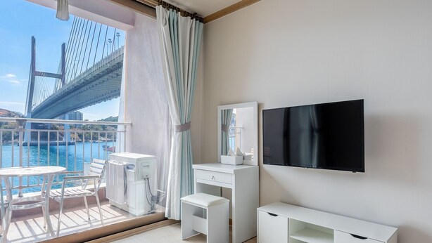 A modern hotel room with a balcony, a TV, a desk, and a chair. - Yeosu Turtleship Pension (Yeosu)