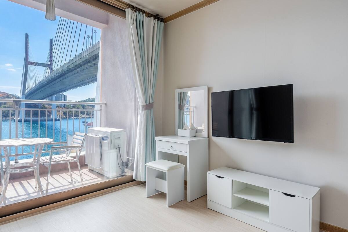 Ein modernes Hotelzimmer mit Balkon, Fernseher, Schreibtisch und Stuhl.