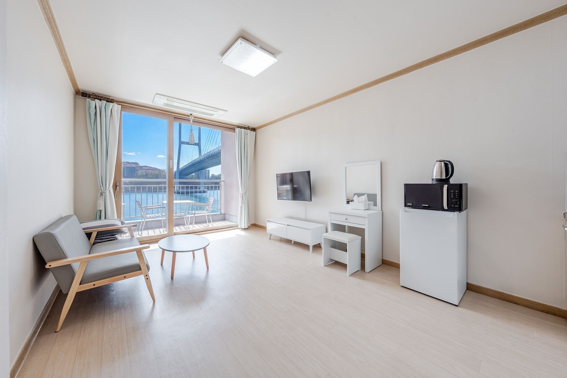 Quarto de hotel moderno com varanda, TV, micro-ondas e área de estar.