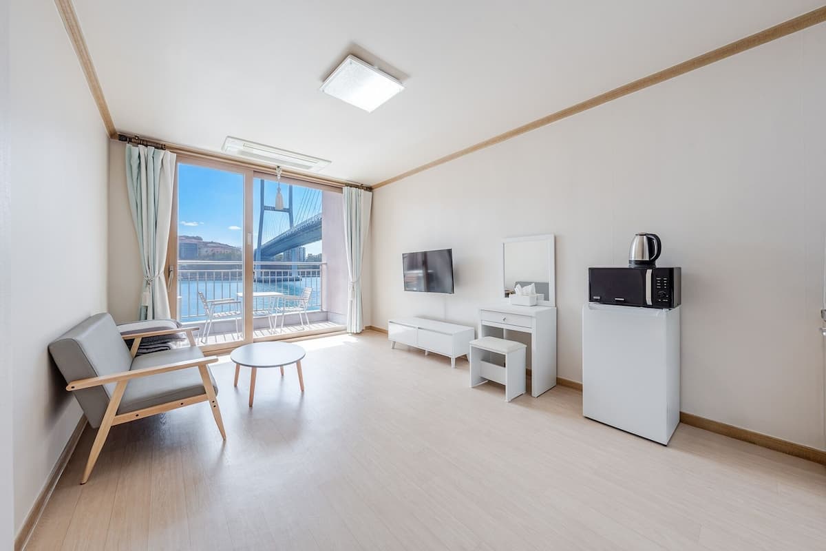 Una habitación de hotel moderna con balcón, televisión, microondas y zona de estar.
