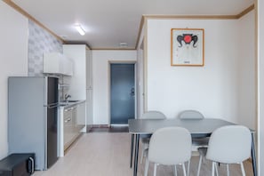 Una cocina compacta con refrigerador, armarios y un comedor con mesa y sillas.