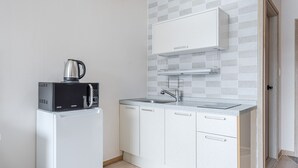 A compact kitchen with a microwave, kettle, sink, and white cabinets. - Yeosu Turtleship Pension (Yeosu)