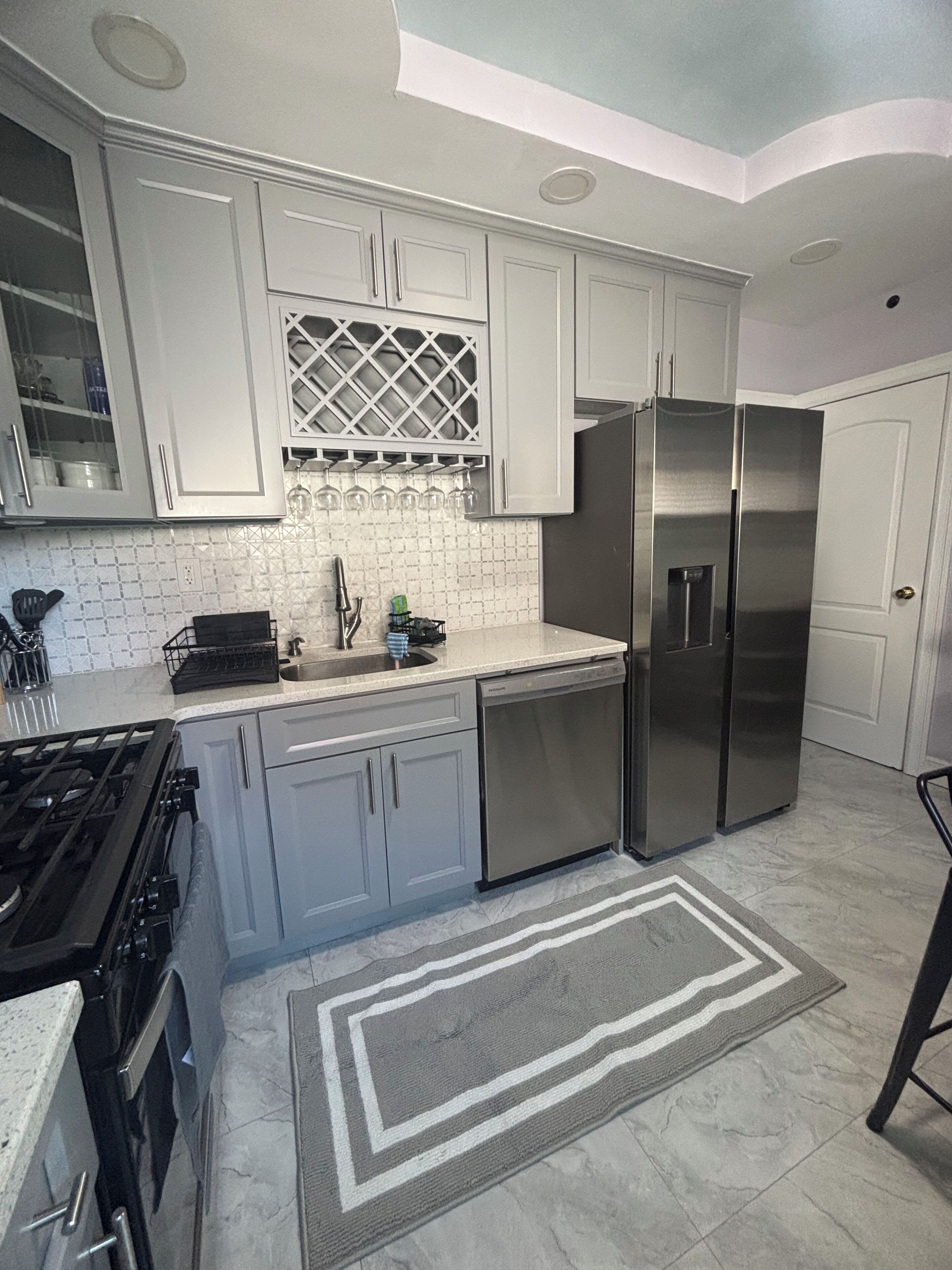 A modern kitchen with white cabinets, stainless steel appliances, and a patterned backsplash.