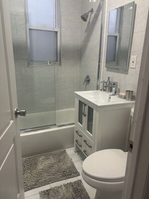 Un baño con ducha, inodoro, lavamanos y armario.