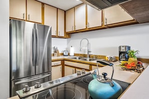 Una cocina moderna con electrodomésticos de acero inoxidable, armarios de madera y una isla central con un hervidor.