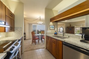 Eine moderne Küche mit Granit-Arbeitsplatten, Holzschränken, einem Backofen und einem Geschirrspüler.