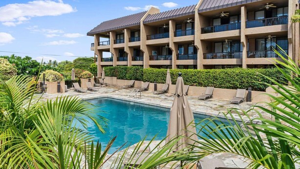 A hotel with a pool, multiple balconies, and lush greenery. - Kona Pacific B411 - Garden View Kona Condo | Walk to Town & Ironman (Kailua Kona)