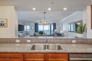 A kitchen with granite countertops, a double sink, and an overhead light fixture. - Beachin' Escape | Destin West Lazy River | Huge Balcony | Bay Views | Sleeps 10 (Fort Walton Beach)
