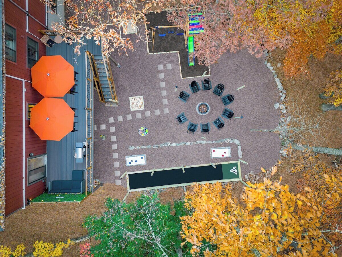 Un espacio al aire libre con una zona de estar, un parque infantil y un edificio de fachada roja.