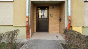 Entrada de un edificio con una puerta, un ventanal pequeño y un cartel con el número del edificio.