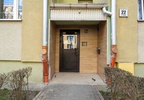 Ein Gebäudeeingang mit einer Tür, einem kleinen Fenster und einem Schild, das die Hausnummer anzeigt.