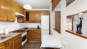 Una cocina con armarios de madera, una estufa, un refrigerador y una mesa con un periódico.