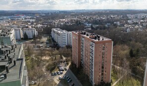 A high-rise building with multiple floors, surrounded by a parking area and trees. - Odrzańska Harmony Apartment (Kraków)