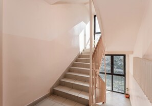A staircase with a wooden railing, leading to a balcony with a view of trees. - Odrzańska Harmony Apartment (Kraków)