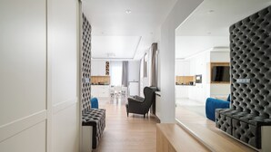 A modern hotel room with a sofa, a chair, a wooden bench, and a large window. - Bielany Spacious Apartment (Warszawa)