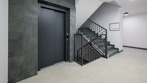 A modern interior with a dark door, a staircase with metal railings, and a sign on the wall. - Hemara Modern Apartment (Warszawa)