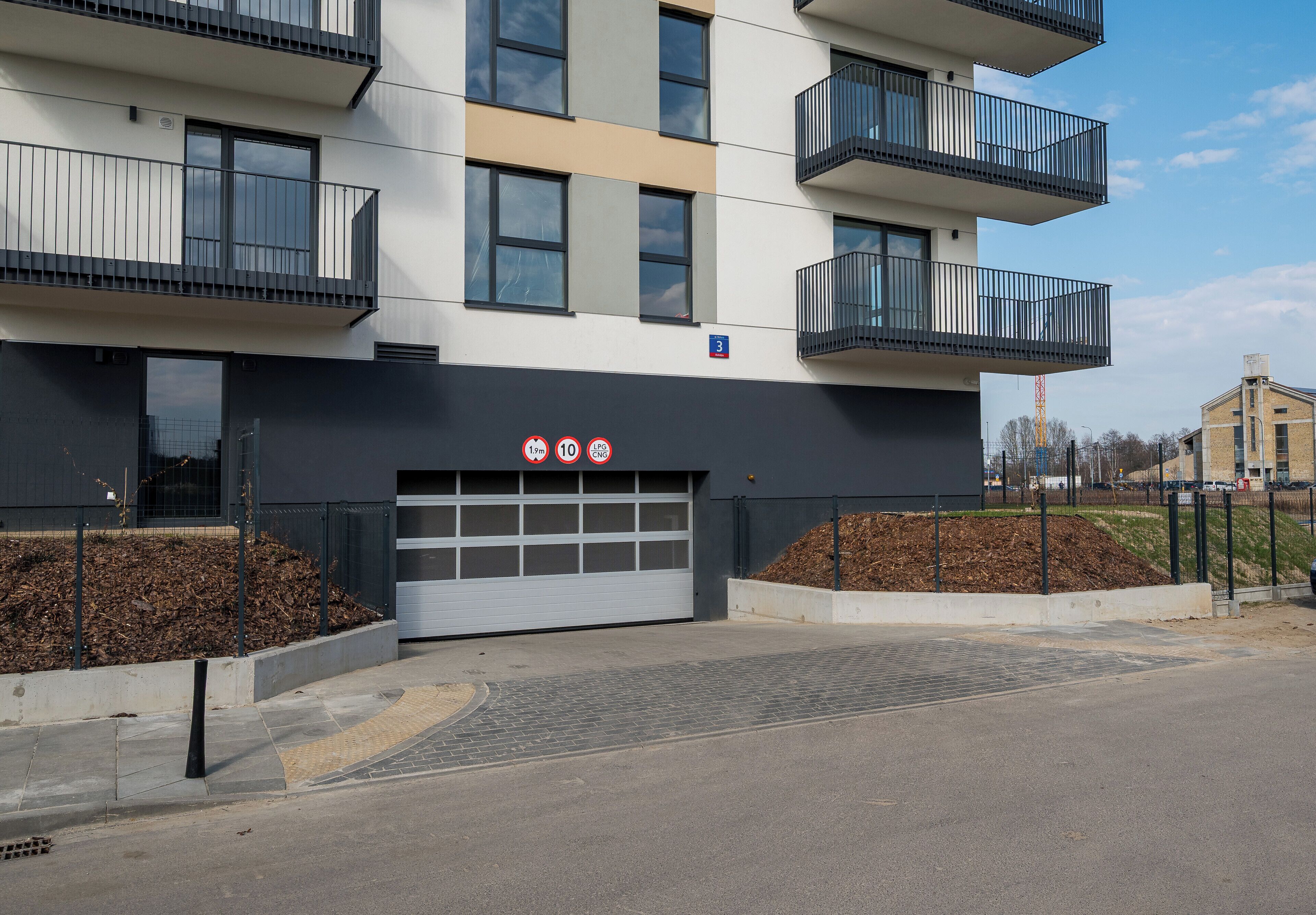 Un immeuble à plusieurs étages doté d’une entrée de garage, de balcons et d’un panneau indiquant qu’il est interdit de se garer.