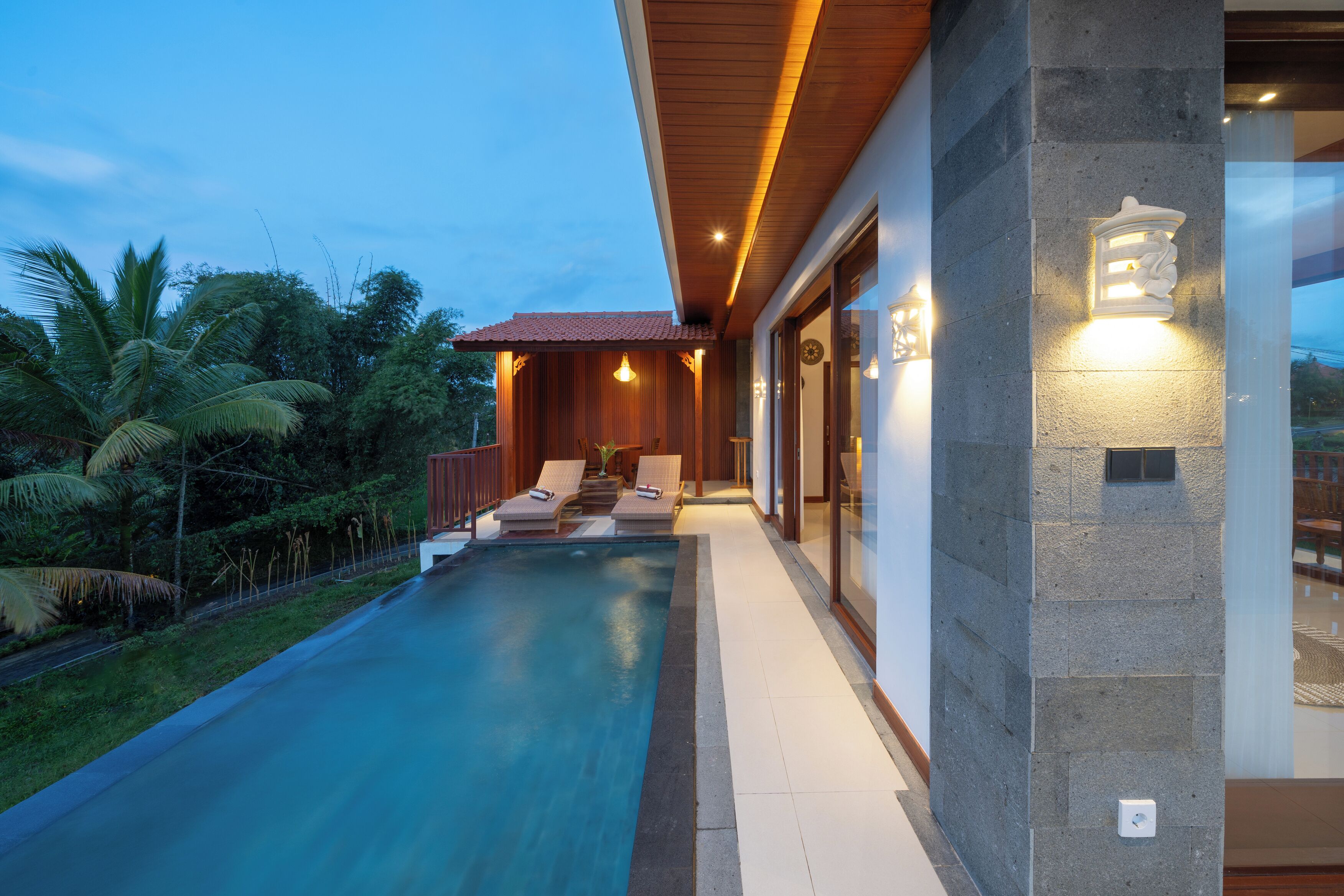 A modern house with a swimming pool, wooden deck, and a stone wall.