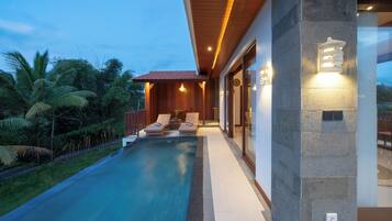 A modern house with a swimming pool, wooden deck, and a stone wall.
