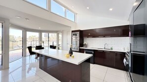 Una cocina moderna con una isla grande, muebles oscuros y vistas al exterior.
