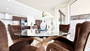 A modern dining area with a glass table, brown upholstered chairs, and a vase with flowers.