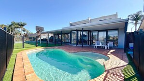 A modern house with a swimming pool, patio furniture, and a glass-enclosed dining area. - Lakefront/View/Swimming Pool/6B4B/Shopping Nearby (Patterson Lakes)