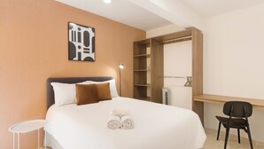 Une chambre d’hôtel équipée d’un lit, d’un bureau, d’une chaise, d’une armoire et d’une œuvre d’art accrochée au mur.