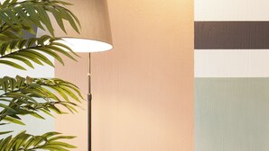 Une chambre moderne avec un lampadaire, une table ronde en bois et un fauteuil rembourré.