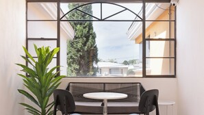 Une pièce dotée d’une grande fenêtre, d’une table ronde, de deux chaises, d’une plante en pot et d’un tapis à rayures.