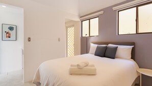 Une chambre à coucher avec un lit, une table de chevet, une fenêtre et une porte.