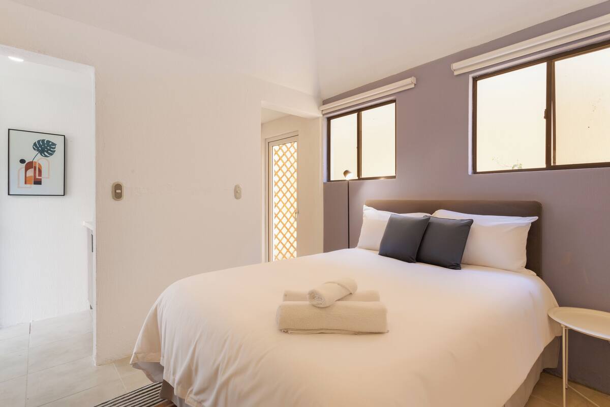 Une chambre à coucher avec un lit, une table de chevet, une fenêtre et une porte.