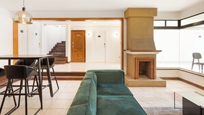 Un salon moderne avec un canapé vert, une table à manger avec des chaises, une cheminée et un escalier menant à une autre pièce.