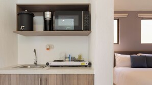 Une petite cuisine équipée d’un four à micro-ondes, d’une machine à café et d’un petit évier.