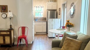A living room with a glass coffee table, a sofa, a red chair, and a kitchen in the background. - Salty Silo Bed & Breakfast, Breakfast upon request prior to arrival please! (Rockport)