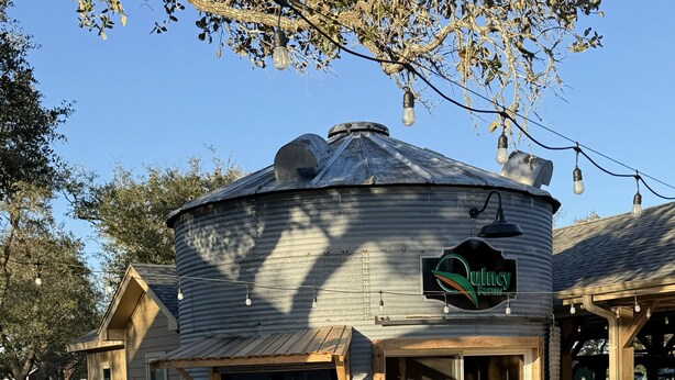 A rustic building with a round silo-like structure, a wooden sign, outdoor seating, and a patio area. - Salty Silo Bed & Breakfast, Breakfast upon request prior to arrival please! (Rockport)