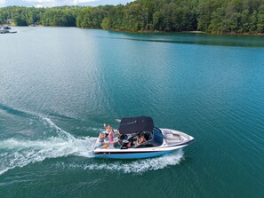 Een speedboot met passagiers op een kalm meer, omringd door dicht bos.