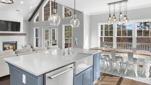 Een moderne keuken met een groot kookeiland, witte kasten en hanglampen.