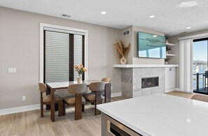 A modern kitchen with a dining area, a fireplace, and a TV mounted on the wall. - Viridian Bellevue - Luxury, roof top deck, private boat slip (Muskegon)