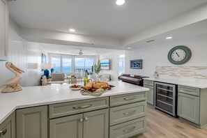 A modern kitchen with a large island, green cabinets, and a view to the outside. - New Listing! Direct Oceanfront 2/2 | Huge Private Balcony | Beachfront Pool | Garage (Ormond Beach)