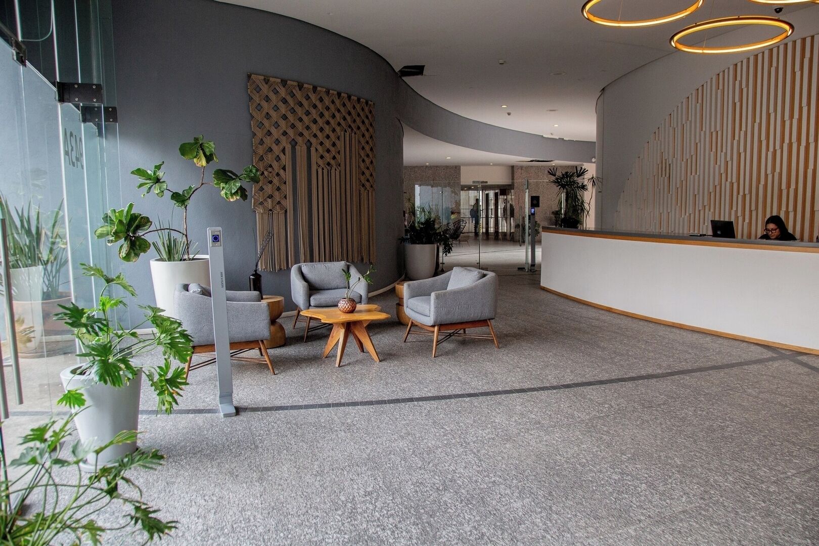 A modern reception area with a curved wall, seating, and potted plants.