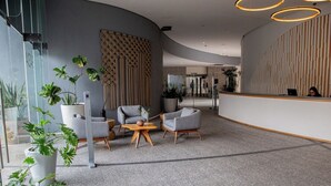 Een moderne receptie met een gebogen wand, zitplaatsen en potplanten.