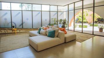 Um interior moderno com um sofá modular, janelas amplas e plantas dentro de casa.