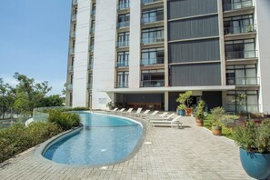 A modern hotel with a swimming pool, lounge chairs, and potted plants. - Mr W | 3BR Large Apartment Pool+Amenities (Zapopan)