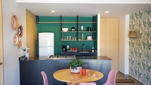 Een moderne keuken met een centraal eiland, een eetgedeelte met roze stoelen en een groene accentmuur.